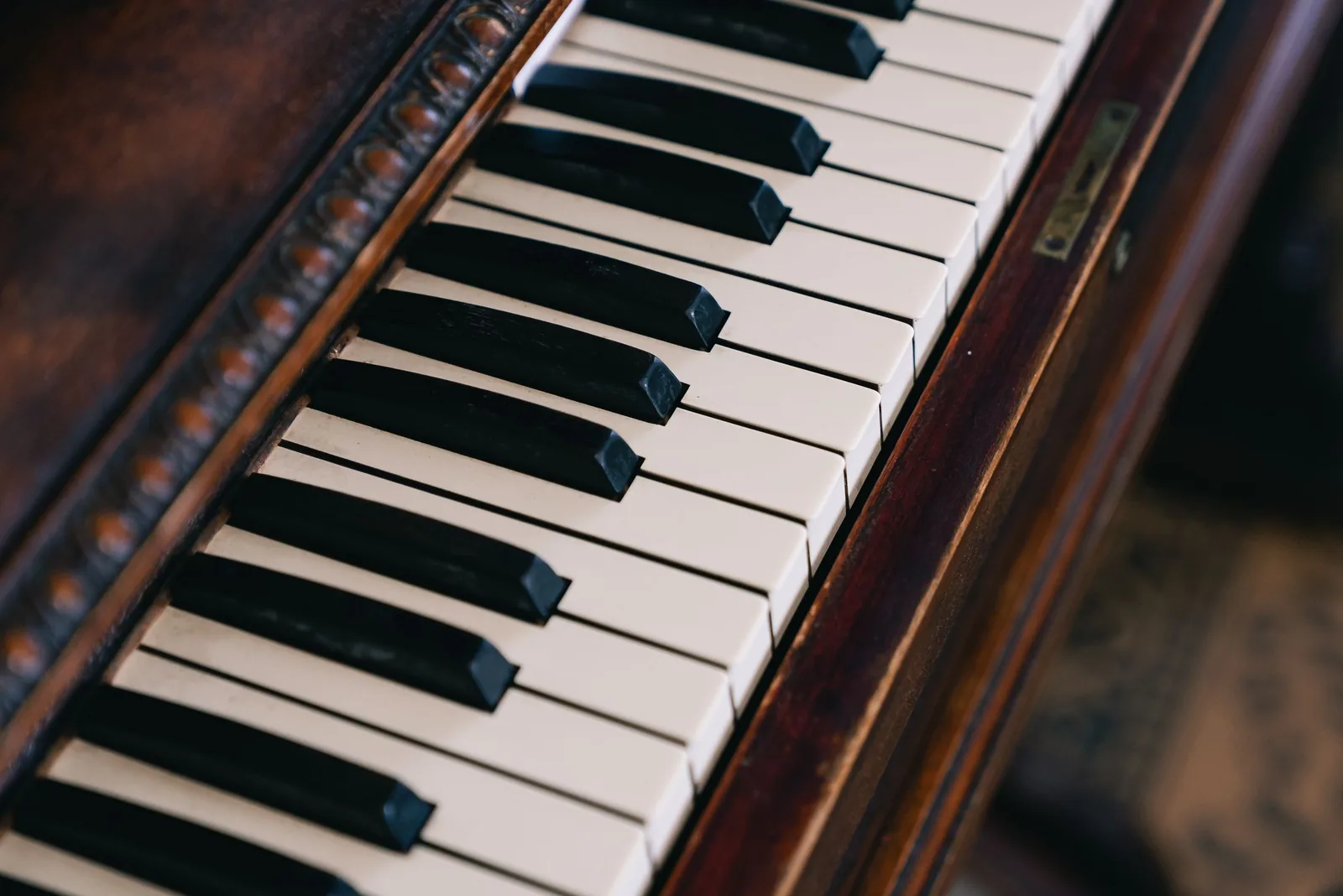 A close view of antique piano keys beside a carved wooden edge
